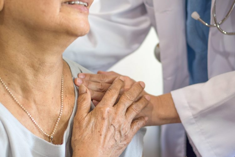 elderly woman holding hand of young doctor