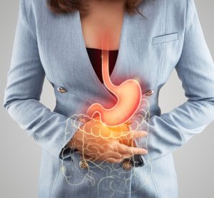 The illustration of stomach and large intestine is on the woman's body against gray background. Acid reflux.