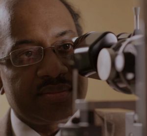 Dr Jayakrishna Ambati looking into a microscope - macular degeneration research [Credit: UVA Health].