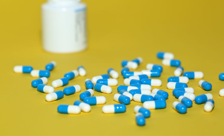 Blue and white caspsules - potentially NSAIDs - on a yellow background