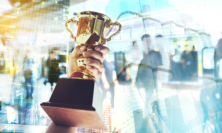 person holding up a gold trophy cup is winner in a competition with cityscape background.