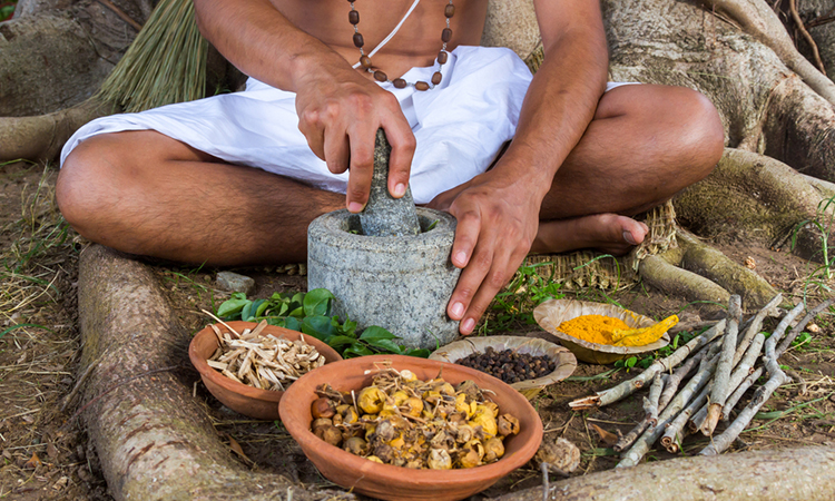 A person preparing ayurvedic medicine in the traditional manner in India