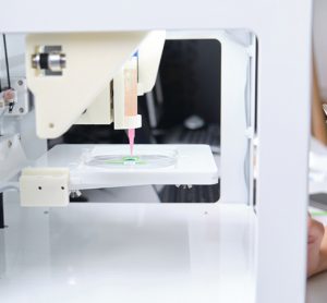 Researcher adjusting a 3D bioprinter to 3D print cells onto an electrode. Biomaterials, tissue engineering concepts.