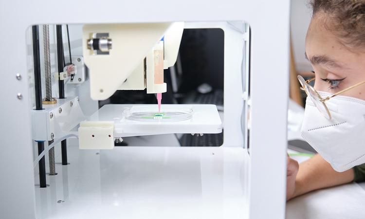 Researcher adjusting a 3D bioprinter to 3D print cells onto an electrode. Biomaterials, tissue engineering concepts.