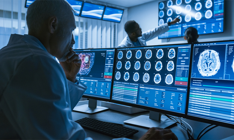 Over the Shoulder Shot of Senior Medical Scientist Working with CT Brain Scan Images on a Personal Computer in Laboratory.