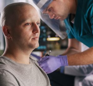 Bald male patient with cancer and doctor injecting a vaccine
