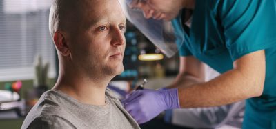 Bald male patient with cancer and doctor injecting a vaccine