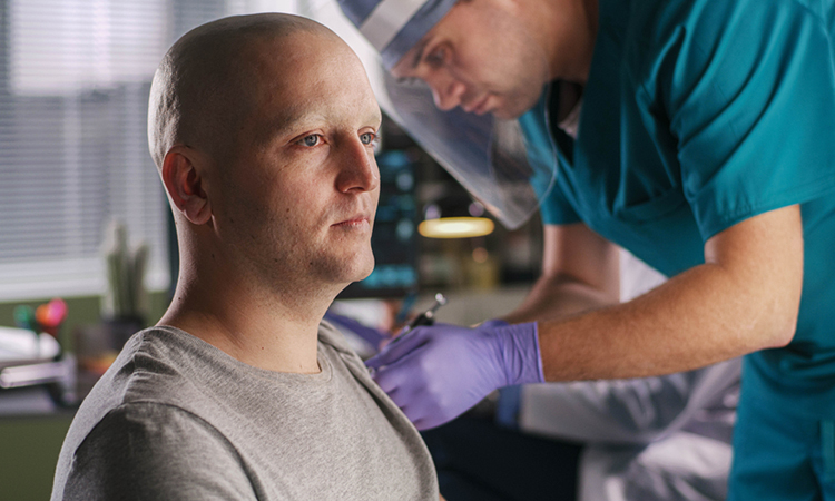 Bald male patient with cancer and doctor injecting a vaccine