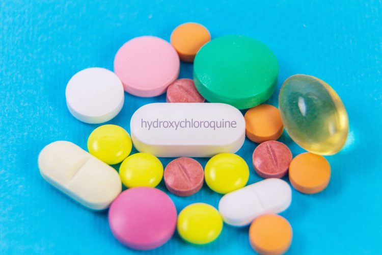 pile of colourful medication tablets with a central white tablet labelled 'hydroxychloroquine'
