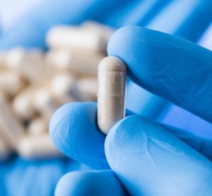 Scientist hands in gloves hold pills