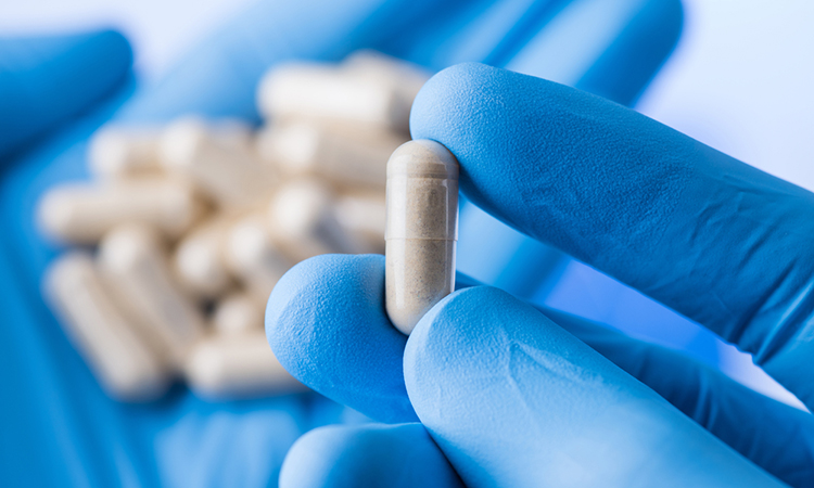 Scientist hands in gloves hold pills