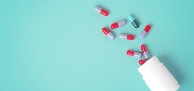 Spilled pills with white medicine bottle on green background