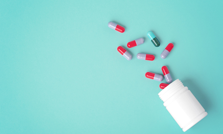 Spilled pills with white medicine bottle on green background