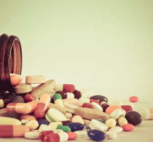 Many type of medical drugs pills capsules and medicine poring from the bottle with isolation background in vintage retro color. Used for manufacturing health industry concept.