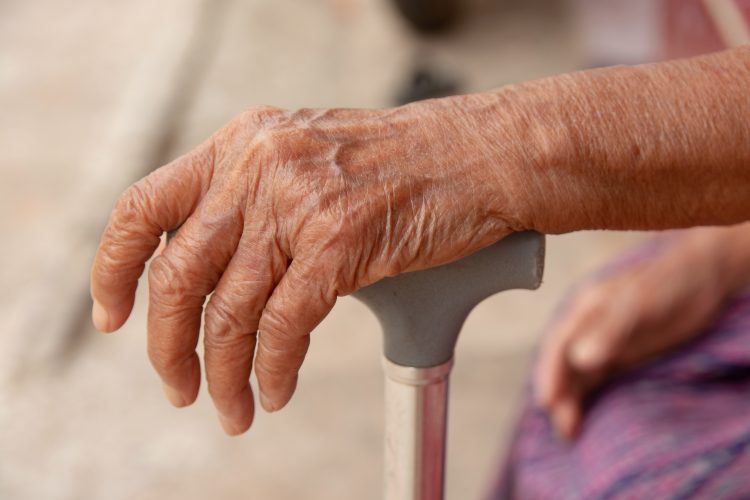 Elderly person's hand holding a walking stick
