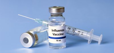 Flu vaccine, syringe, and vials on light blue background