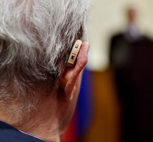 Detail shot with a hearing aid device used by old man during conference