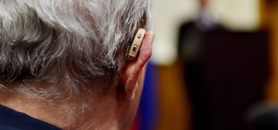 Detail shot with a hearing aid device used by old man during conference