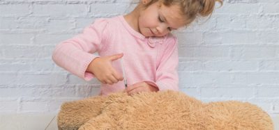 child, a girl makes a shot to the toy bear, the insulin syringe
