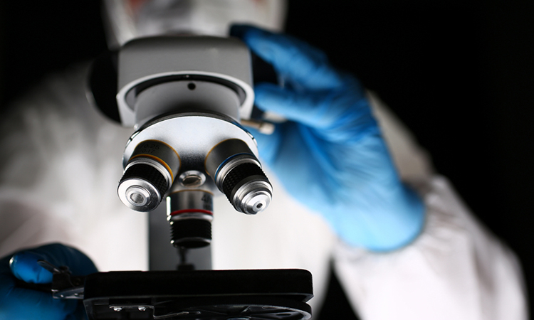 Laboratory Pharmacist Work at Optical Microscope. Scientist Working on Research with Microscopy Metal Lens. Pharmaceutical Lab. Chemist in Coverall Analyzing Experiment with Medical Equipment.