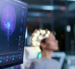 Woman Wearing Brainwave Scanning Headset Sits in a Chair In the Modern Brain Study Laboratory/ Neurological Research Center. Monitors Show EEG Reading and Brain Model.
