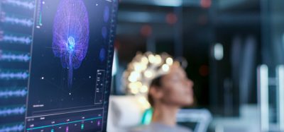 Woman Wearing Brainwave Scanning Headset Sits in a Chair In the Modern Brain Study Laboratory/ Neurological Research Center. Monitors Show EEG Reading and Brain Model.