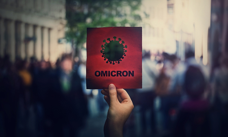 Omicron the new variant of the Covid-19 virus, coronavirus mutations, sars-cov-2 strain. Hand holds red banner warning in the crowded streets.