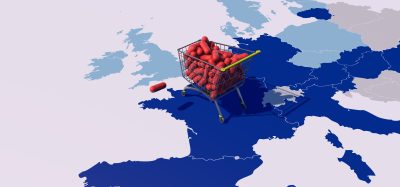 Shopping cart filled with red capsules placed on a map of Europe and the UK, symbolizing access and regulation of medicines.