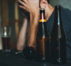Depressed man next to beer bottles