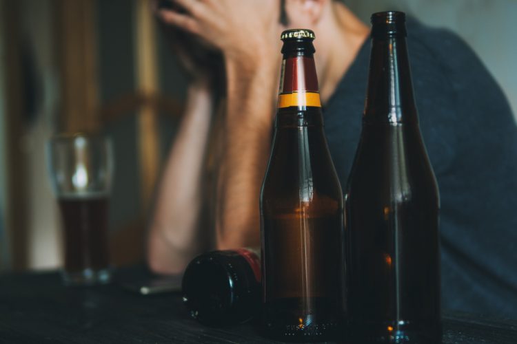 Depressed man next to beer bottles