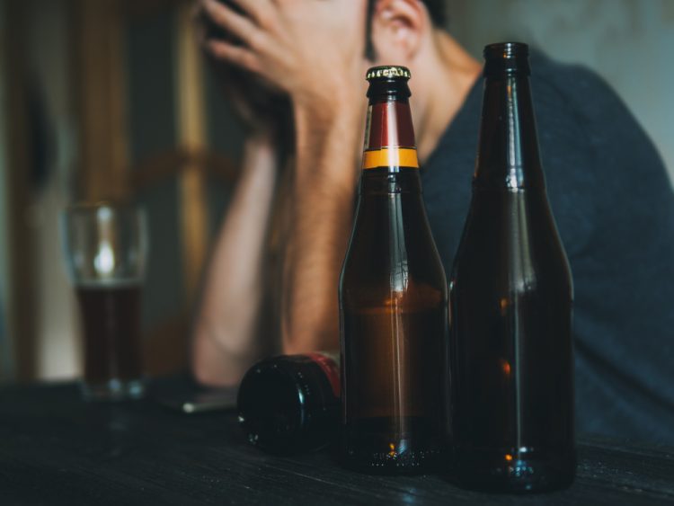 Depressed man next to beer bottles