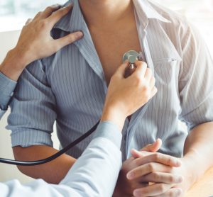 Doctor measuring arterial blood pressure using stethoscope