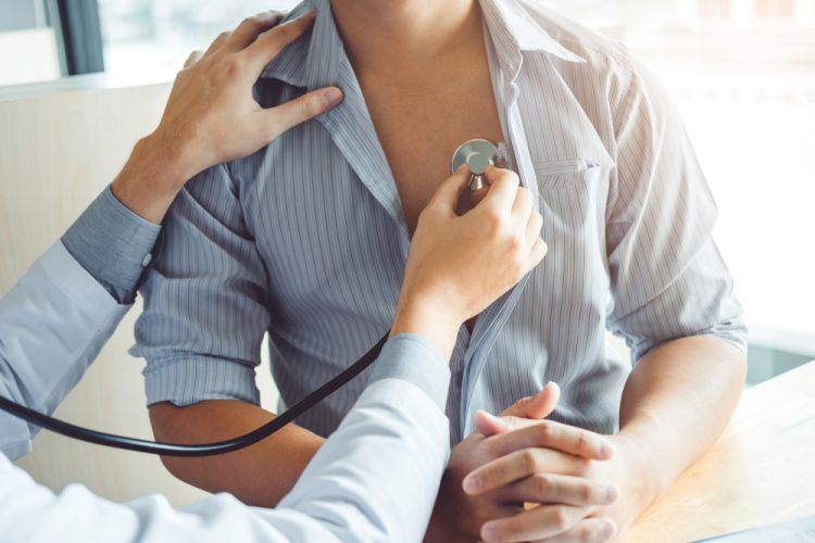 Doctor measuring arterial blood pressure using stethoscope