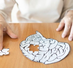 Elderly woman putting last piece of brain shaped puzzle