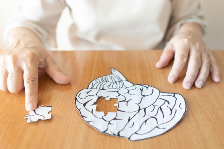 Elderly woman putting last piece of brain shaped puzzle