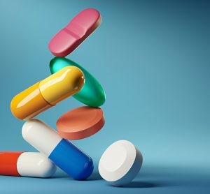 A group of medicine pills and antibiotics balancing on top of each other.