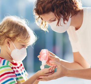 Mother handing child hand sanitiser