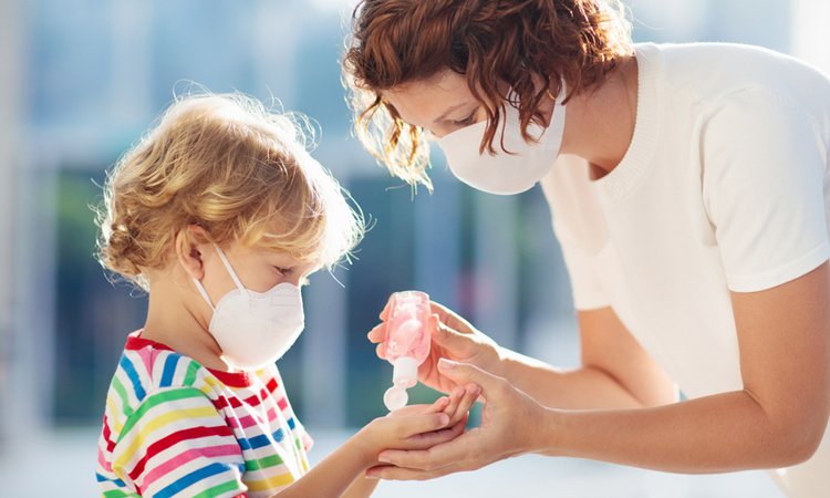 Mother handing child hand sanitiser