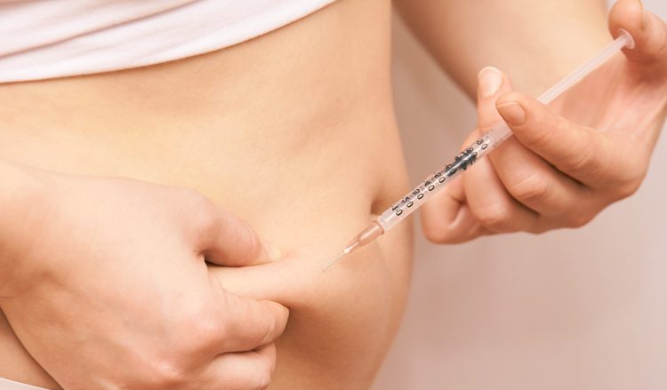 Woman injecting substance in the abdominal area