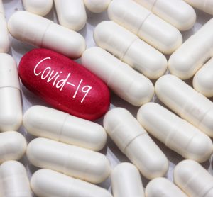 White pills surrounding one red pill that is labelled Covid-19