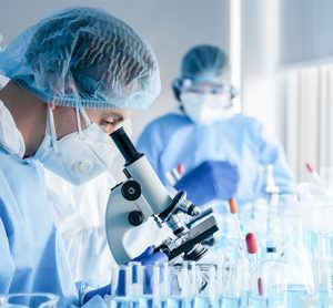 biochemical research scientist team working with microscope for coronavirus vaccine development in pharmaceutical research labolatory, selective focus