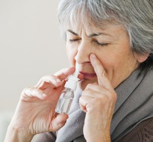 Elderly woman using nose spary