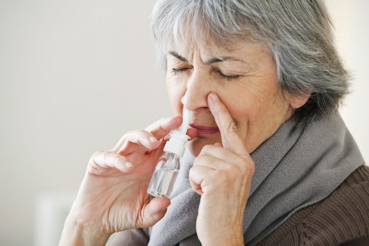 Elderly woman using nose spary