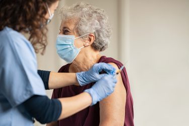 GP vaccinating old patient