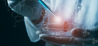 A scientist uses a pipette over a petri dish with digital molecular and chemical structure graphics, representing innovation and predictive modelling in drug discovery.