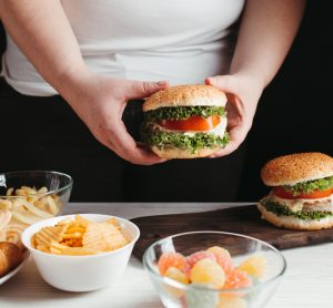 Overweight man behind table of junk food
