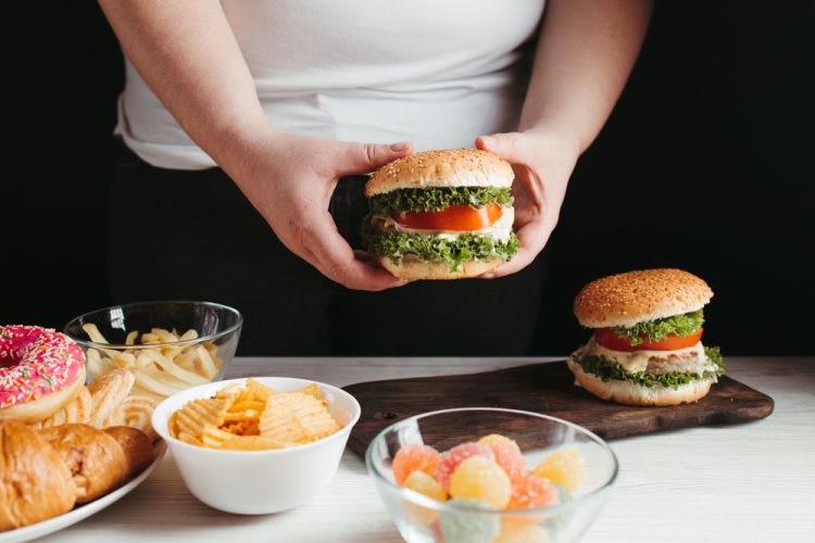 Overweight man behind table of junk food