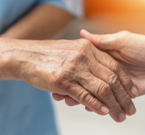 Hand of Alzheimer's patient holding nurse's hand