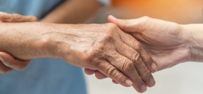 Hand of Alzheimer's patient holding nurse's hand
