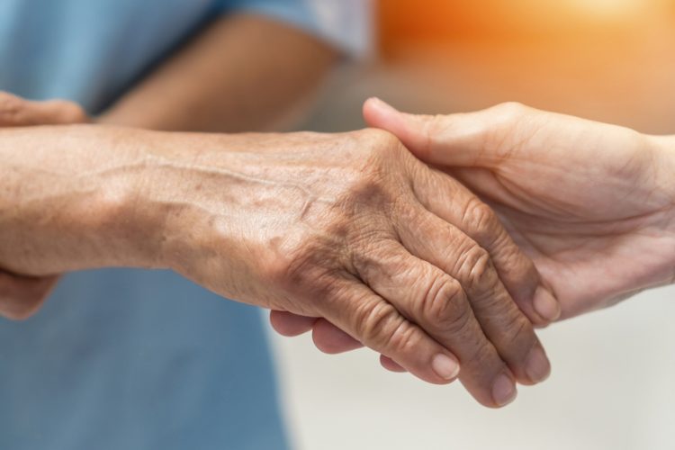 Hand of Alzheimer's patient holding nurse's hand